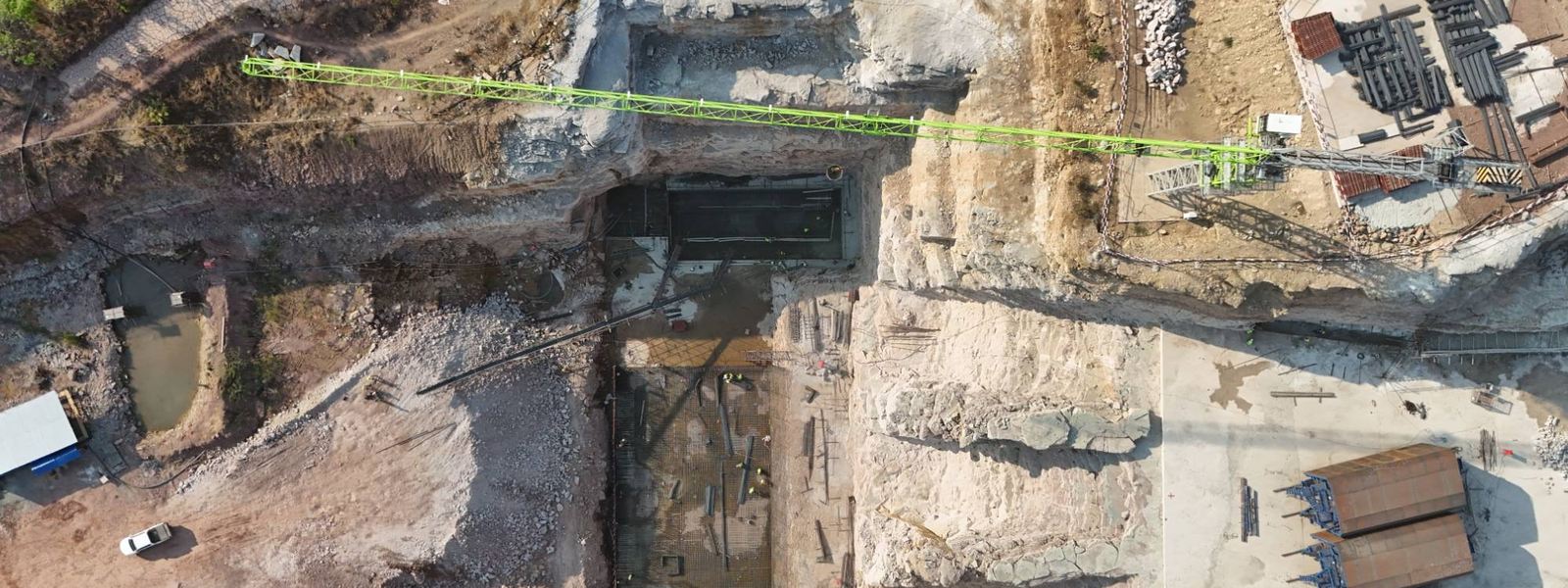 Drone view looking straight down into the powerhouse pit, with the tower crane jib across it