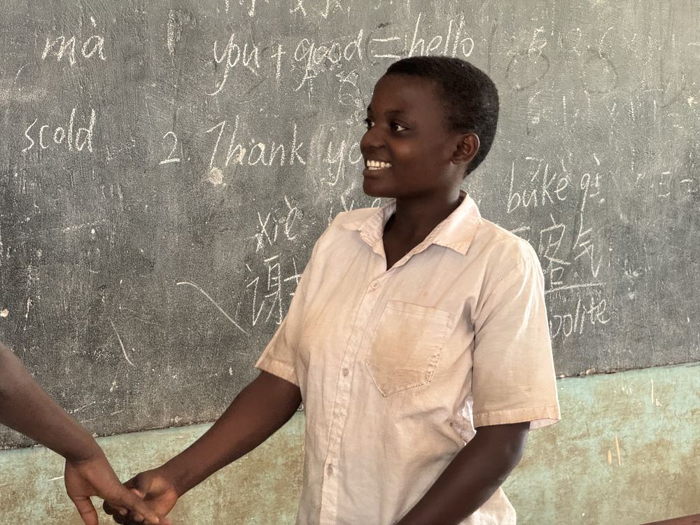 A pupil smiling at the blackboard covered with Chinese characters and pinyin