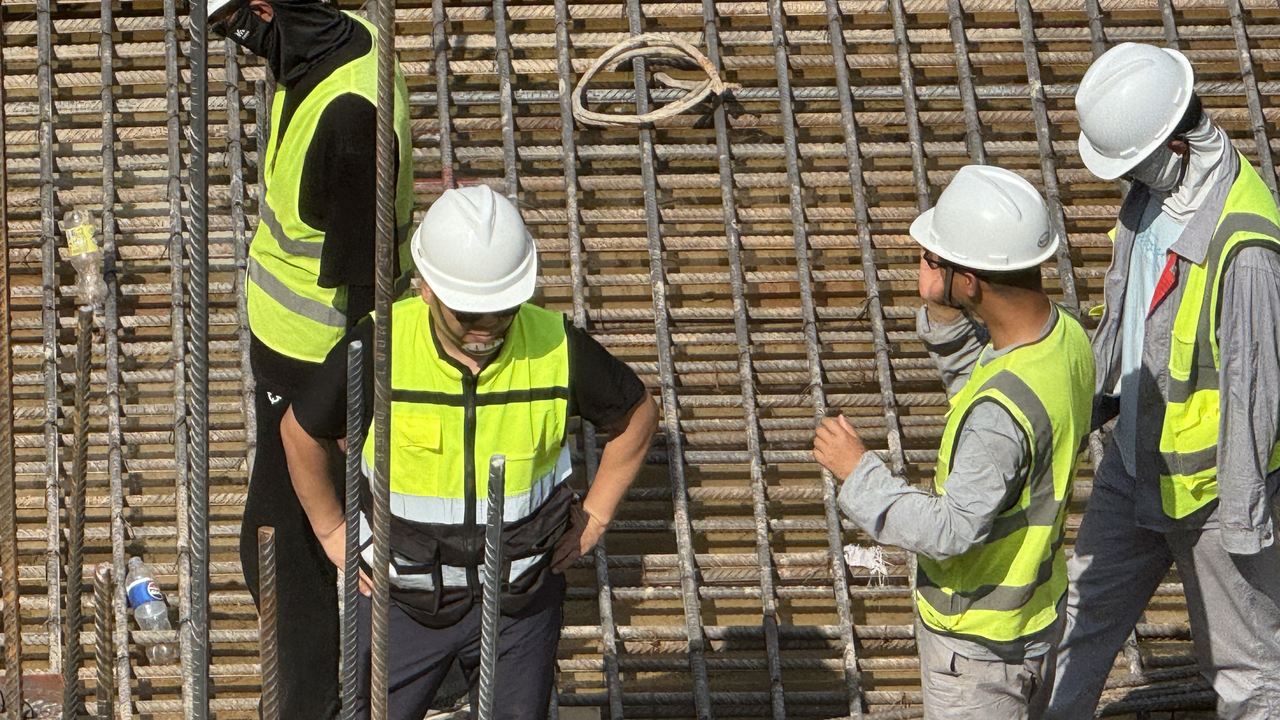Engineers in hard hats inspecting the reinforcement