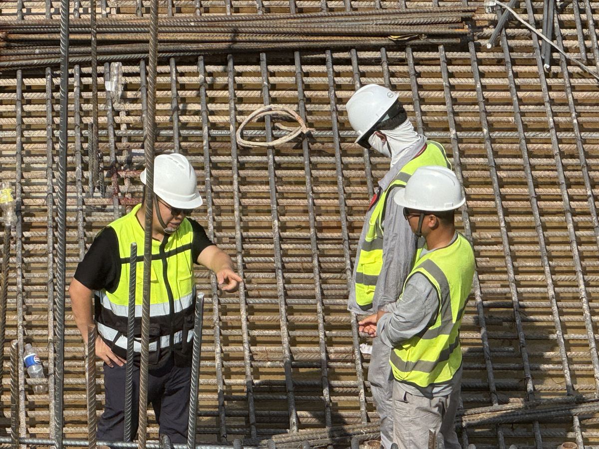 Engineers in hard hats inspecting the reinforcement mat