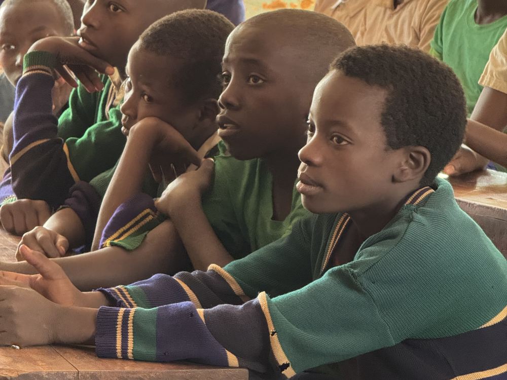 Pupils in green school jumpers listening closely
