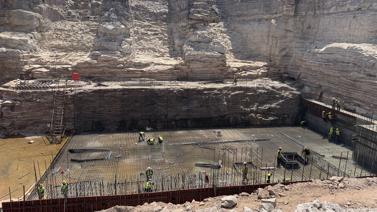 Workers on the reinforcement mat of the powerhouse foundation slab below the rock walls