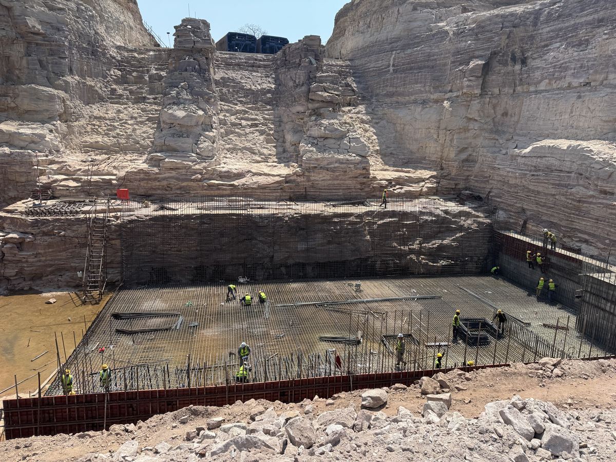 Workers on the reinforcement mat of the powerhouse foundation slab below the rock walls