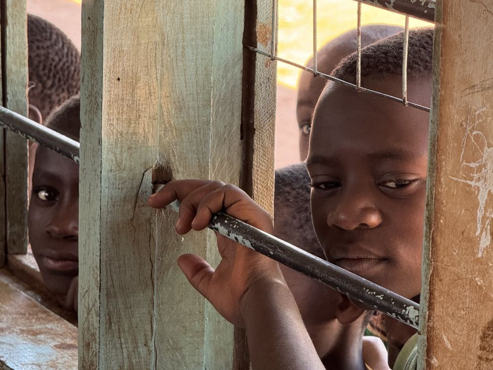 Children looking into the classroom through the window bars