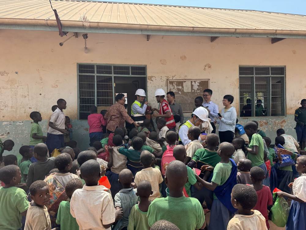 Project staff handing sweets and gifts to pupils