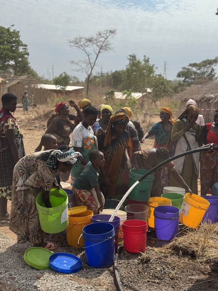 Women and children filling colourful buckets from the new supply