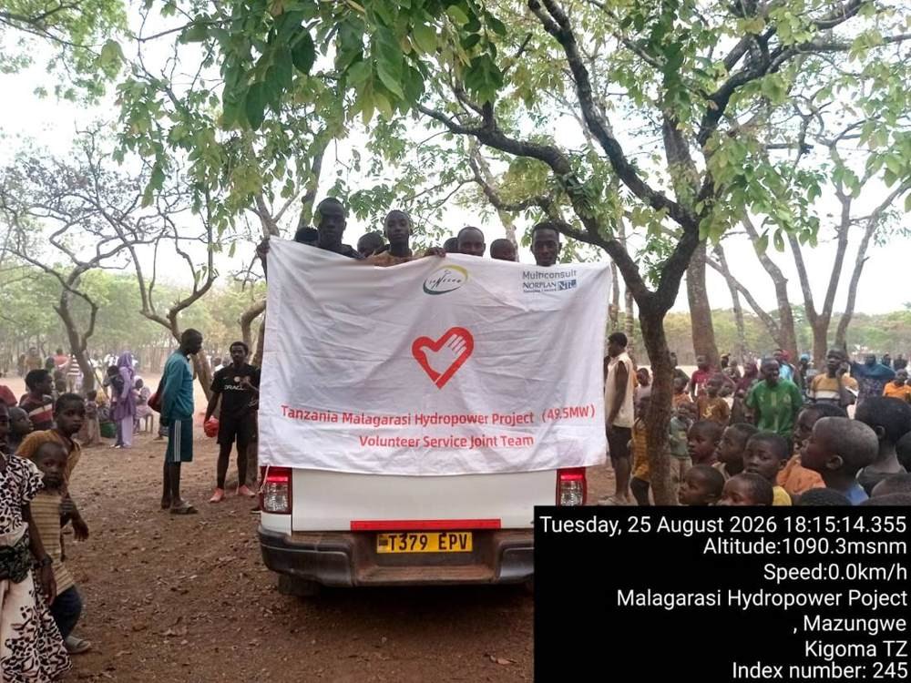 Project pickup with the Volunteer Service Joint Team banner surrounded by villagers