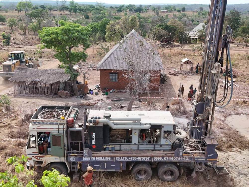 Drilling rig working beside village houses, aerial view