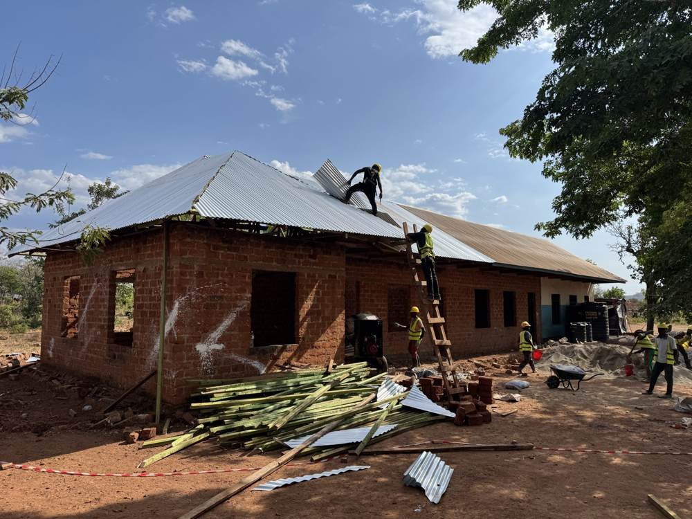 Workers laying sheeting on the classroom roof